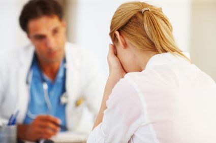 blonde woman upset with her head in hands talking to doctor