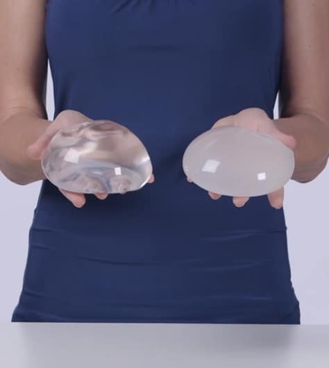 woman holding silicone and saline breast implant