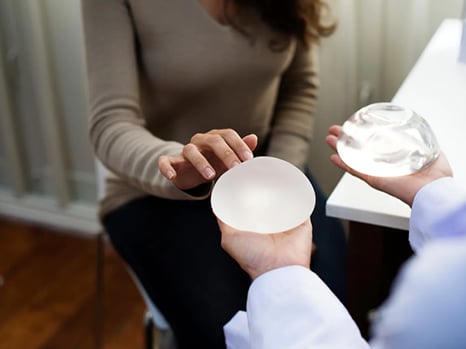 woman touching feeling silicone saline breast implant