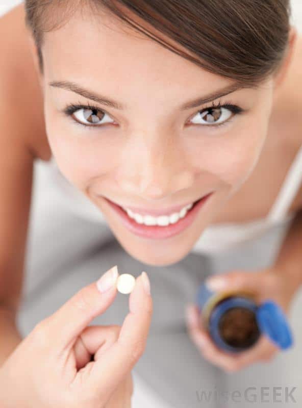 woman smiling with pill in her hand